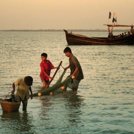 Tres niños pescando en la marea baja en la isla de Maheshkhali, Bangladesh
