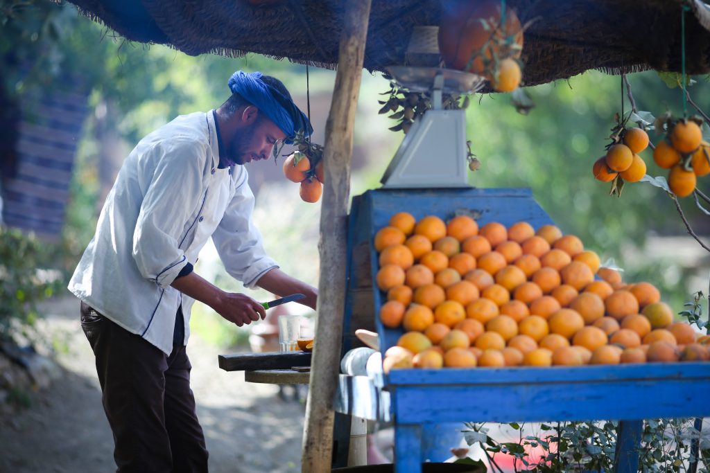 Marrakech, Marruecos - 4 de octubre de 2018: Puesto de jugo fresco - el vendedor está cortando naranjas y preparándose para exprimir jugo de naranjas locales cultivadas en las cercanías