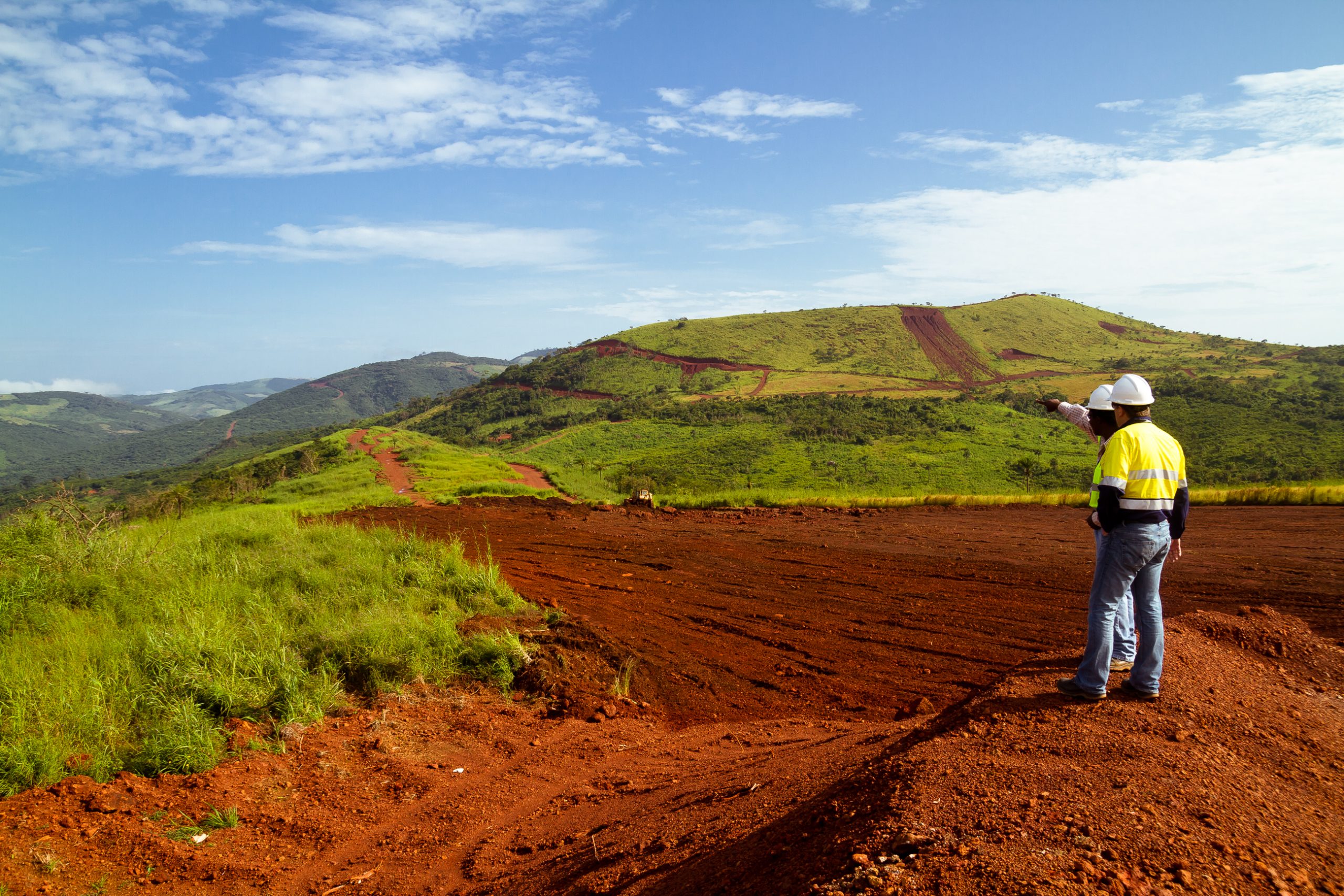 Two construction men in an open field, preparing to start a building project.