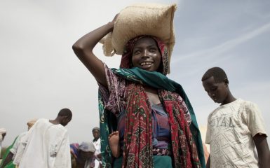 La femme photographiée vit dans le village de Kassira, au Tchad. Elle tient en équilibre sur sa tête un sac de maïs reçu lors d'une distribution alimentaire dans la région du Guéra. Chaque famille a reçu 34 kilos de maïs, 4 à 5 kilos de haricots, 2.25 litres d'huile et un peu de sel. Oxfam et le Programme alimentaire mondial (PAM) ont travaillé en partenariat sur la distribution. Photo : Abbie Trayler-Smith/Oxfam