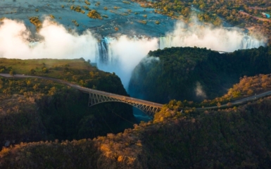 A bridge is in front of the iconic Victoria Falls.