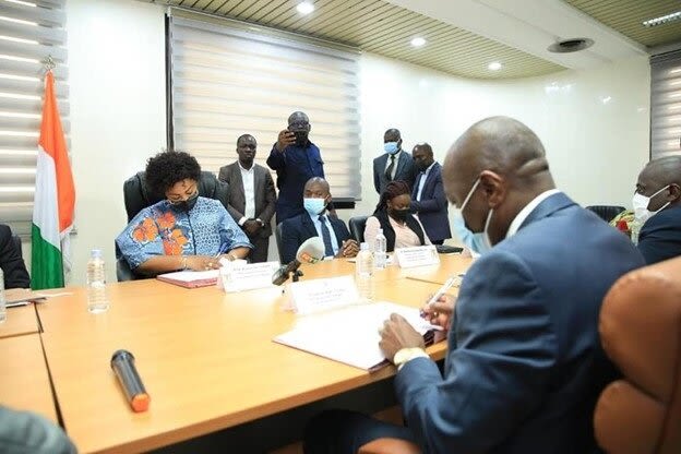Two ministry officials sign documents on a table.