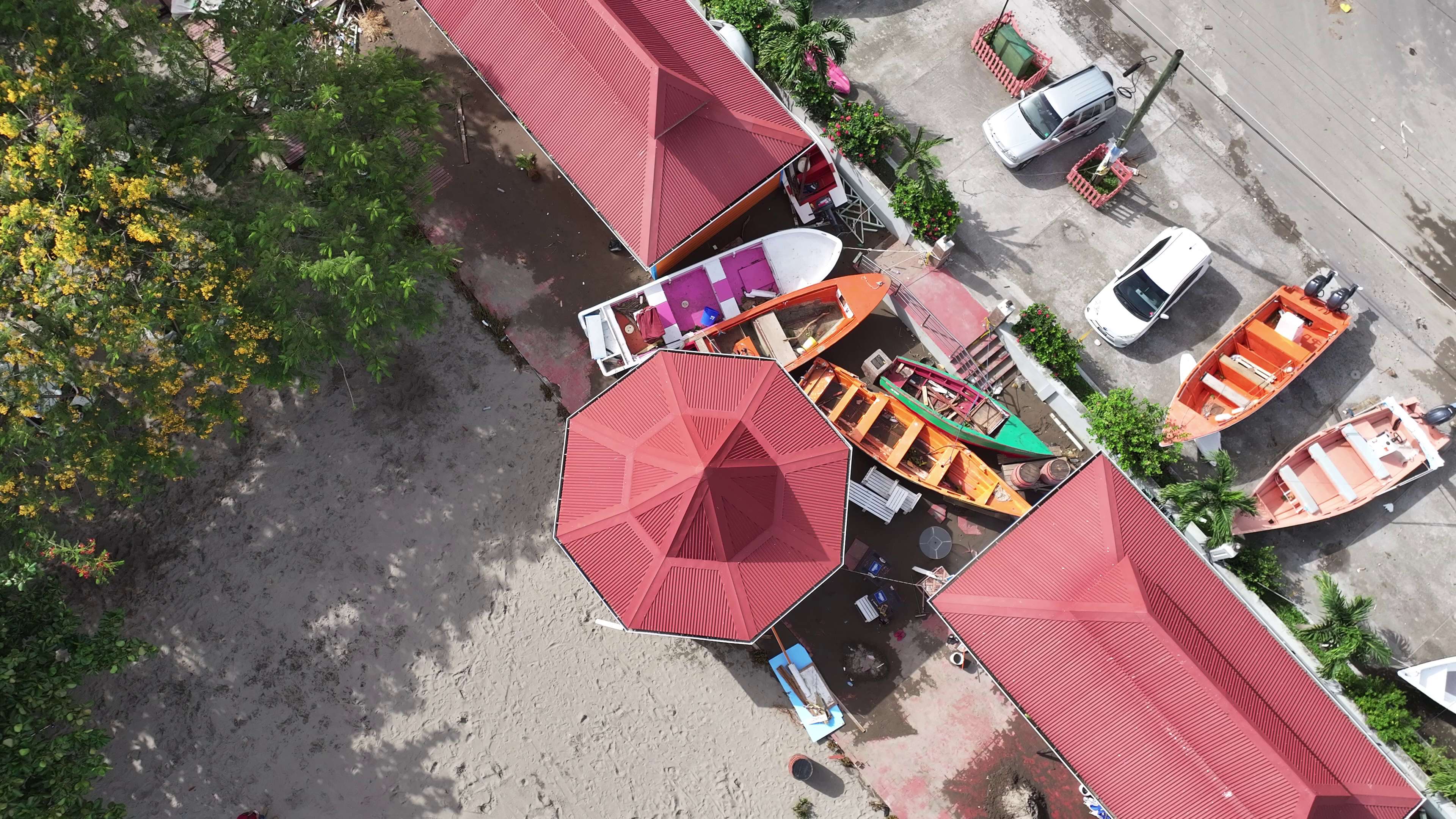 Aerial view of red-roofed buildings along a shoreline with small fishing boats and canoes that appeared damaged.