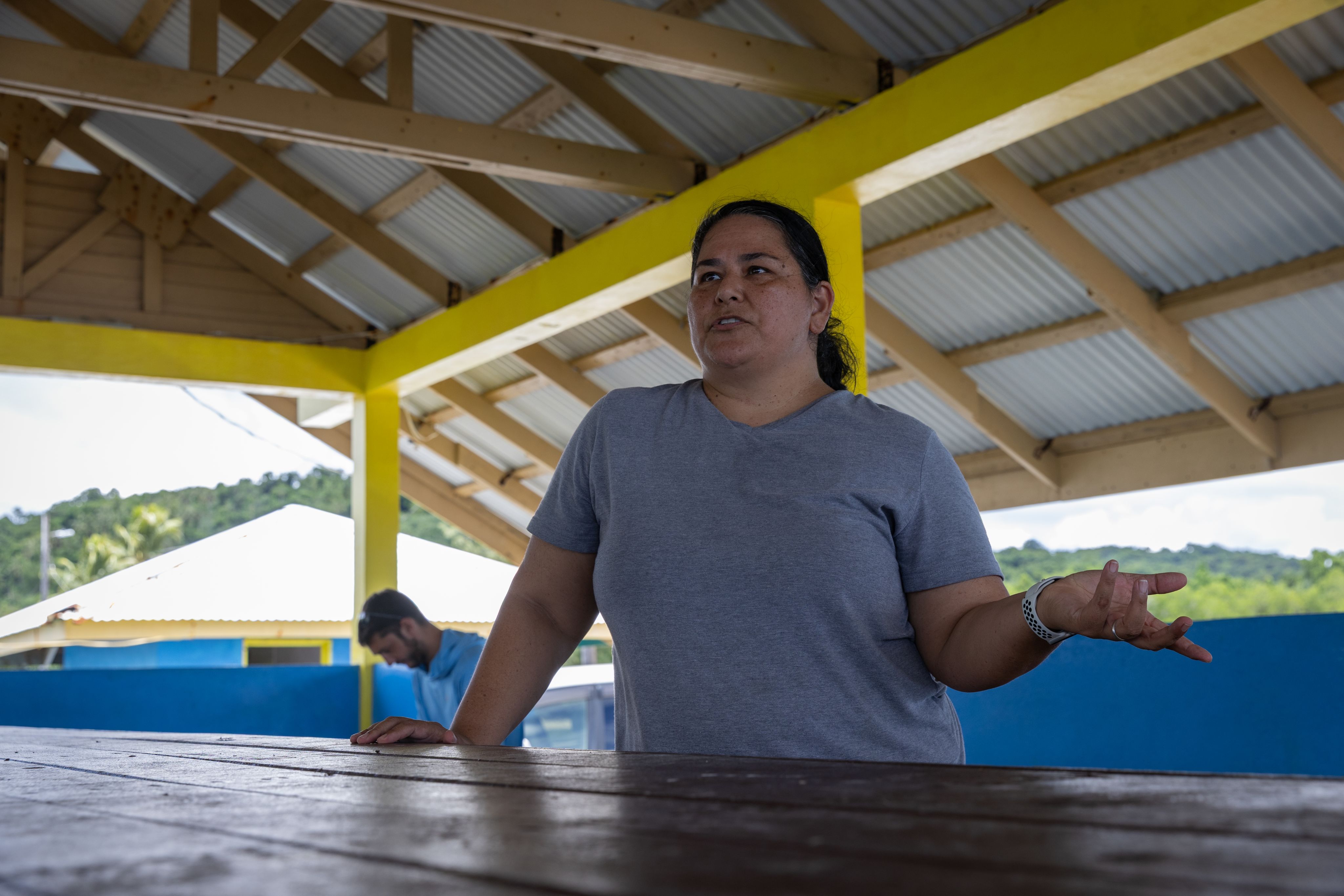 A woman standing behind a desk talking. 