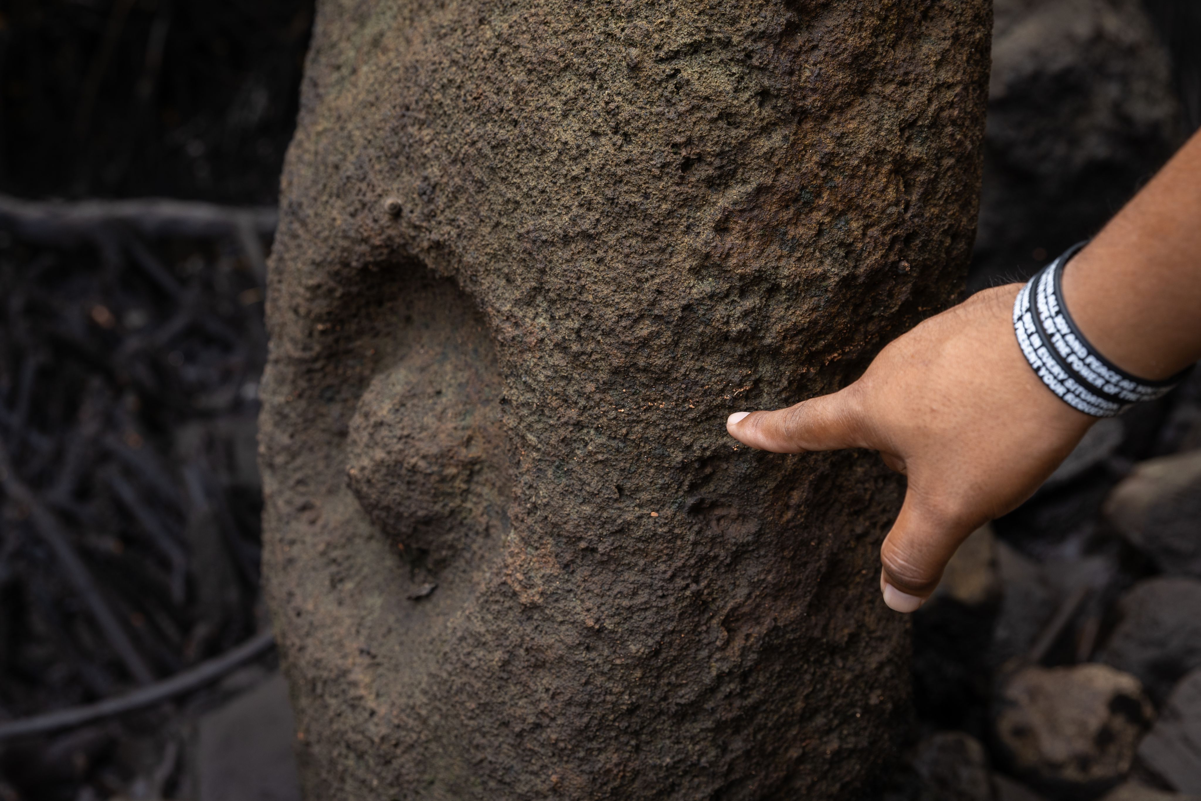 A hand pointing to a marking on a carved stone face. 