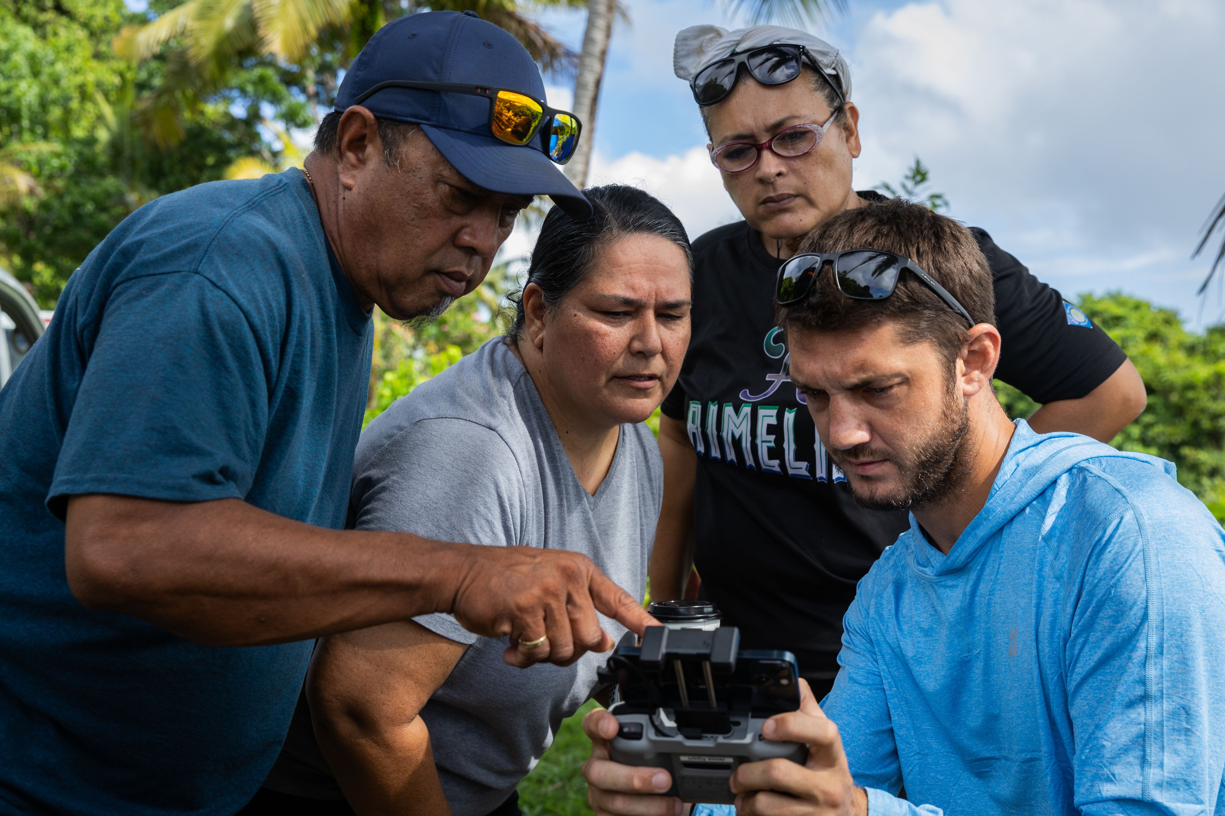 Four people gather around a device used for mapping. 