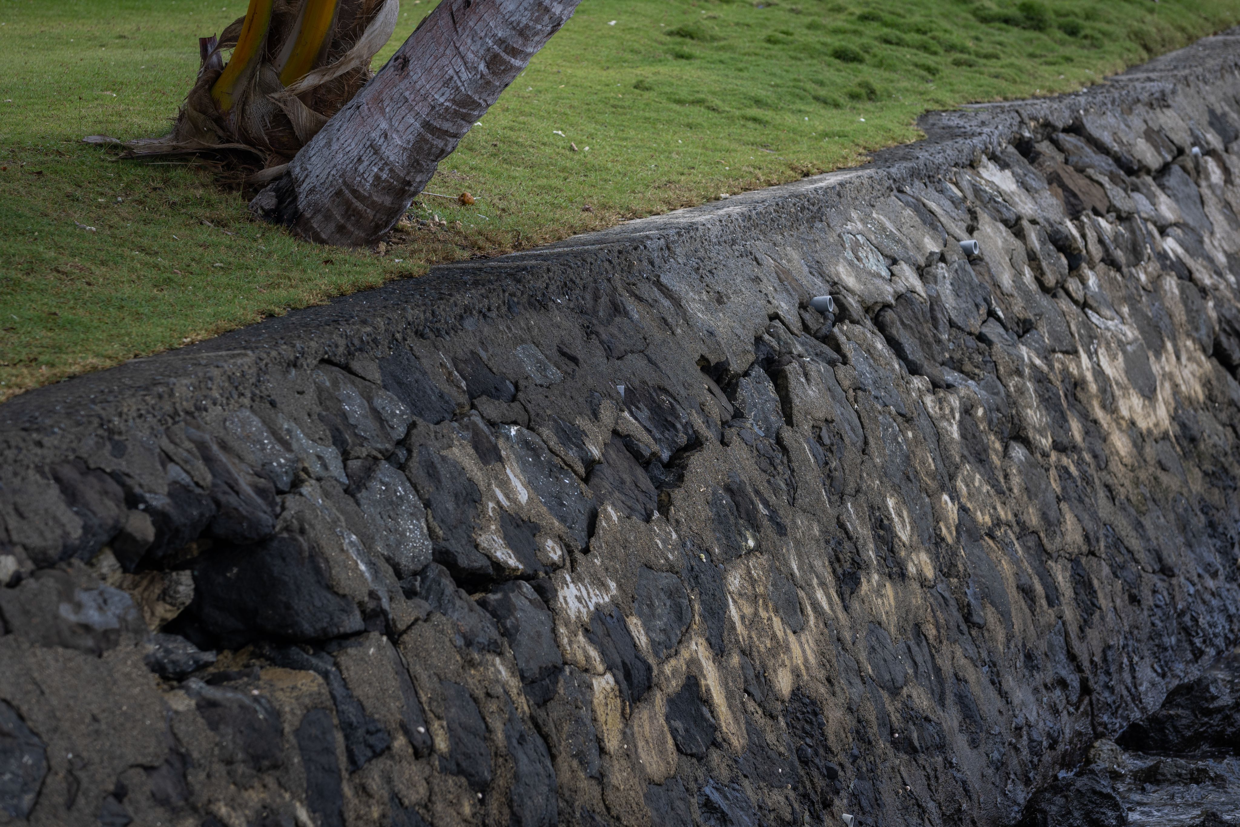 A stone wall with cracks from rising sea levels.